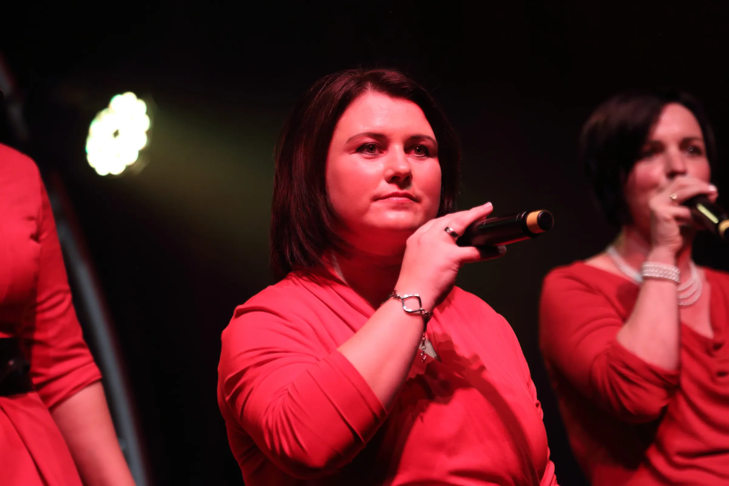 Zwei Sängerinnen in Rot singen im Scheinwerferlicht